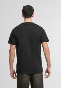 Svart bomulls T-skjorte med korte ermer, rund halsdesign, glatt tekstur, og ingen synlige mønstre eller grafikk på baksiden.
