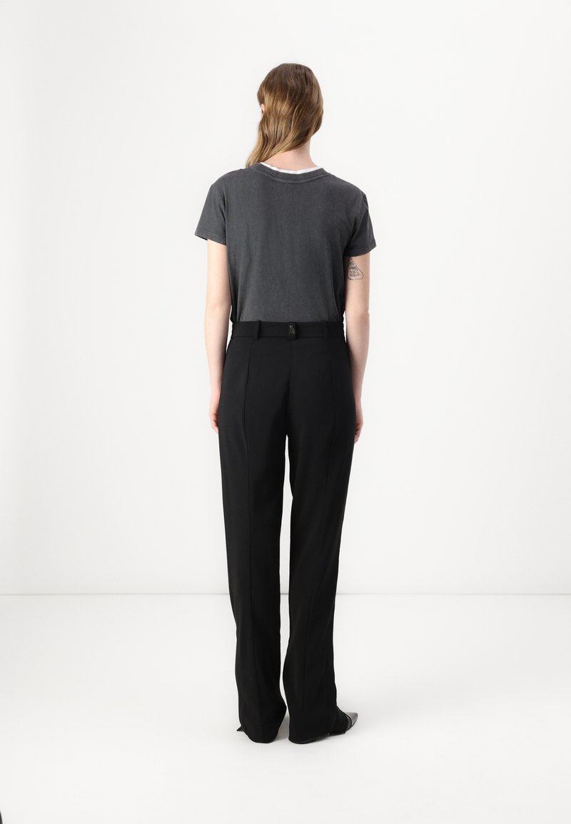 Szara bawełniana koszulka z okrągłym dekoltem, zestawiona z czarnymi spodniami o wysokim stanie, z paskiem i zwężanymi nogawkami.