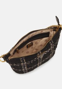 Sac bandoulière en tweed noir avec fermeture éclair, quincaillerie dorée et doublure beige à motif avec une étiquette logo et des poches intérieures.