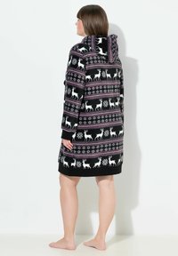 Vestito a gonna con cappuccio nero, caratterizzato da motivi di renne e fiocchi di neve bianchi, con dettagli a strisce viola e rosa. Tessuto morbido e texturizzato.