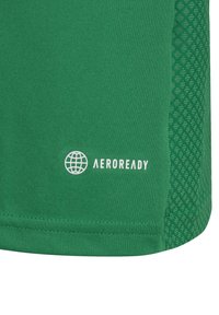 Maglietta sportiva verde con un tessuto liscio e un pannello laterale in mesh testurizzato. Logo "AEROREADY" stampato in bianco vicino all'orlo.