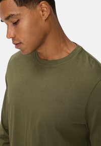 Olijfgroen langpoloshirt van gladde katoen, met een ronde halslijn en een subtiel reliëflogo op de borst.