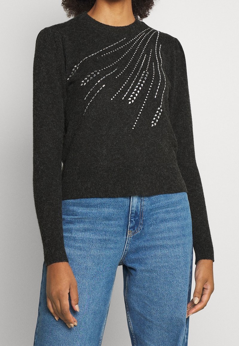 Schwarzer gestrickter Pullover mit langen Ärmeln und einem gerippten Ausschnitt, der silberne Verzierungen in einem fließenden Muster über die Vorderseite zeigt.