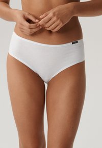 Białe bawełniane majtki hipster z miękkim elastycznym pasem i małym czarnym logo po boku. Gładka tekstura, minimalistyczny design.