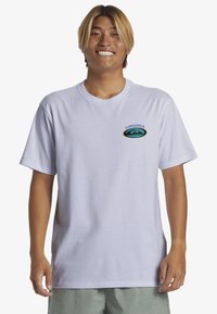 Camiseta de algodón blanca con mangas cortas, que cuenta con un logo multicolor de Quiksilver en el área del pecho izquierdo. Diseño simple, cuello redondo.