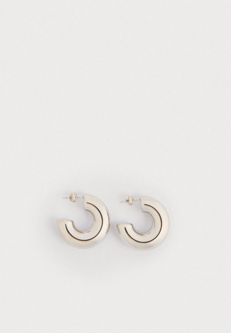 Cercei din metal cu un design curbat, având un finisaj argintiu lustruit și linii subțiri de accent negru. Prindere cu tijă pentru fixare.