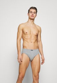 Graue Baumwollslips mit enganliegender Passform, ausgestattet mit einem weichen elastischen Bund und einem schlichten Design, präsentiert an einem Modell.