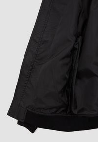 Interior de chaqueta de cuero negra con forro negro liso y puños negros acanalados. Cuenta con dos bolsillos interiores y un diseño elegante.