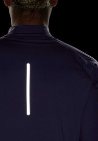 Marine sportshirt met een reflecterende verticale strook op de achterkant. Heeft een aansluitend ontwerp en een gladde textuur, ideaal voor zichtbaarheid bij weinig licht.