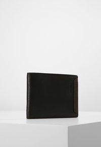 Portafoglio pieghevole realizzato in pelle nera liscia con un accento marrone. Presenta una superficie texturizzata e dettagli di cucitura visibili. Design compatto.