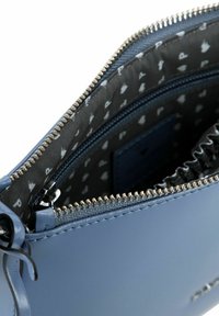 Bustina in pelle blu con cerniera argento, fodera dettagliata con motivo ripetuto e tasca interna con zip per l'organizzazione.