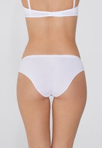Slip in cotone bianco con finitura liscia e design minimalista, dotato di un elastico a vita bassa e bordi senza cuciture.