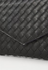 Clutch nera intrecciata in pelle testurizzata, con un design a busta caratterizzato da distintivi motivi a rombo e un bordo piegato.