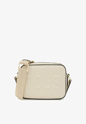Bolso cruzado beige con diseño en relieve "TOUS", material texturizado, ribete negro y correa ajustable para un uso versátil.