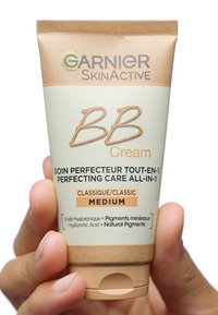 BB Cream-tube i en kombination av ljusgrön och beige, med flip-top lock. Innehåller text som framhäver "Garnier SkinActive", "Classic" och "Medium."
