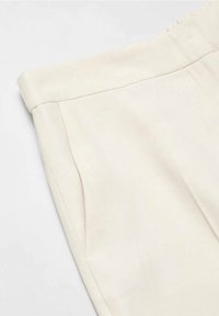 Beige kalhoty z texturované látky se bočními kapsami a plochým pasem, s hladkým povrchem a čistými liniemi.