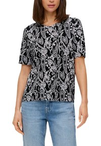 Zwarte korte mouwen top met een witte paisleypatroon. Geweven stof, ronde halslijn en een losse pasvorm. Gecombineerd met lichtblauwe jeans.