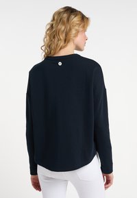Felpa a maniche lunghe blu navy con orlo arrotondato e dettaglio in bottone argentato sul retro. Tessuto morbido con spalle leggermente cadenti.