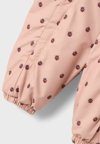Roze kinderbuitensuit met een patroon van zwarte en rode lieveheersbeestjes, elastische manchetten en een gladde, lichte stof.