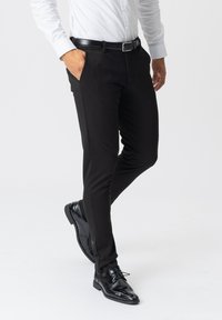 Sorte, slim-fit bukser lavet af et glat stof, med sidelommer og bæltestrop, parret med sorte dress sko.