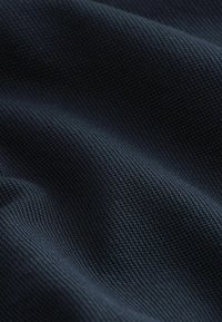 Tejido de un azul marino oscuro con un patrón texturizado y acanalado, que muestra un acabado suave y una trama densa. Ideal para diversas aplicaciones textiles.