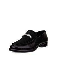 Mocassins en cuir noir avec une tige en daim, présentant un accent argenté sur le devant. Bout rond et petit talon plat.