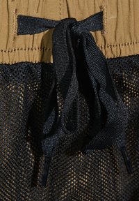 Zwarte mesh stof met een tan elastische tailleband. Bevat verstelbare zwarte koorden en een textuur oppervlak. Geen zichtbare patronen of extra hardware.