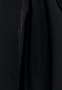 Must kangas pehme ja veidi tekstureeritud pinnaga, ripub õrnade voldikute ja varjudega lähivaates.