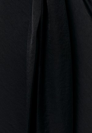 Tissu noir avec une surface douce et légèrement texturée, suspendu avec des plis doux et des ombres en vue rapprochée.