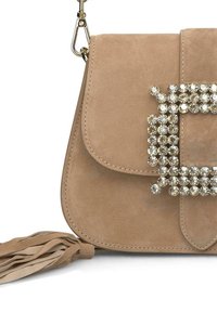 Beige suède handtas met een met kristallen versierde vierkante gesp, een omgevouwen klep en een kwastdetail aan de zijkant. Gladde textuur.