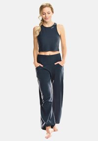 Top corto atlético de un oscuro azul marino combinado con pantalones de corte suelto a juego. La tela parece suave, con bolsillos prácticos y un diseño relajado.