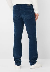 Navy corduroy broek met een rechte pasvorm, voorzien van twee achterzakken en een subtiele ribbelstructuur, gecombineerd met witte sneakers.