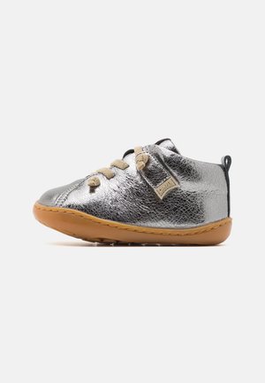 Scarpa in pelle metallica argento con punta tonda, suola in gomma beige, lacci color beige e un piccolo anello sul retro per facilitarne l'indossamento.