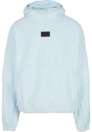 Ljusblå fleecepullover med halvdragkedja, med ett texturerat tyg, sänkta axlar och en liten svart logotyp på framsidan.