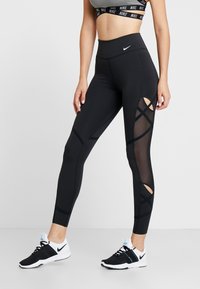 Czarne legginsy o wysokim stanzie z siateczkowymi wstawkami i skrzyżowanymi wycięciami po bokach. Wykonane z elastycznego materiału, z małym logo Nike.