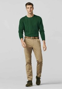 Dark green cable knit sweater, khaki pants, and dark green shoes with a patterned belt. The outfit features smooth textures and classic designs.