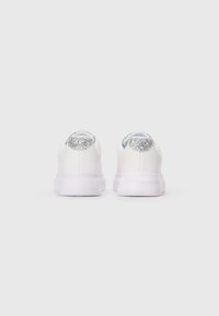 Weiße Sneaker aus glattem Leder, mit einem glitzernden silbernen Akzent an der Ferse und einer transparenten Gummisohle.