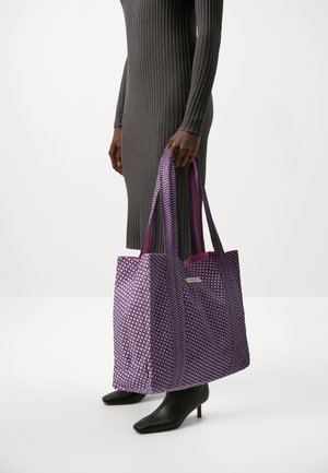 Violetti kuviollinen laukku leveillä kahvoilla ja sileällä pinnalla. Sisustus on tummanvioletti. Yhdistetty tiukkaan harmaaseen ribbimekkoon ja mustiin korkokenkiin.