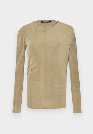 Blusa de manga longa em bege claro, fabricada em um tecido macio com um leve brilho. Apresenta detalhe franzido na lateral e um discreto decote barco.