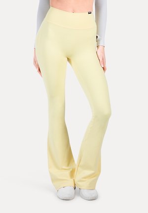 Uppvikta yoga byxor i mjukt och stretcht tyg i gult med hög midja. Slät textur med en elegant silhuett och inga synliga logotyper.