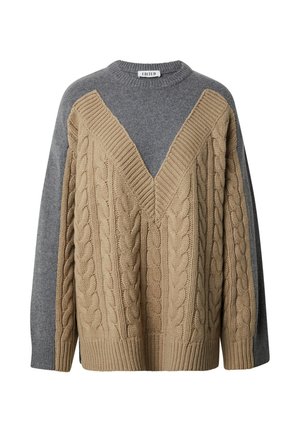 Breton gebreide trui met een V-hals in beige en grijs. Het lichaam is textuur met een kabelpatroon, in contrast met de gladde grijze mouwen.