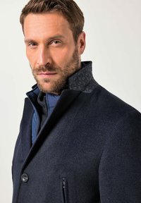 Granatowy płaszcz z mieszanki wełny o strukturalnym wykończeniu, z wysokim kołnierzem ozdobionym wzorem oraz kieszeniami na suwak dla funkcjonalności.