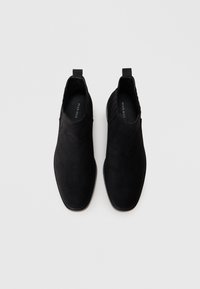 Čierne semišové členkové topánky s hladkým povrchom, elastickými bočnými panelmi a minimalistickým dizajnom. Plochá podrážka, elegantný silueta.