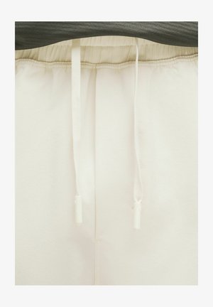 Pantaloni de trening albi cu talie elastică și șnur, având o textură netedă și linii clare. Fără modele sau accente vizibile.