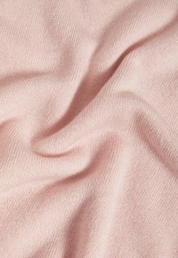 Tessuto lavorato a maglia rosa che mostra una texture morbida con sottili variazioni di tonalità e una caduta fluida, creando morbidi pieghe e contorni.