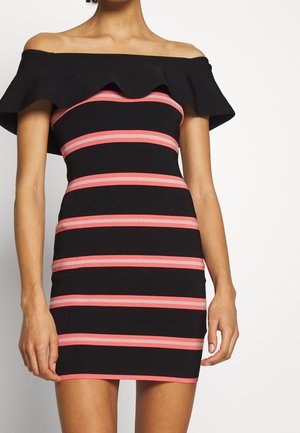 Frau trägt ein schwarzes, schulterfreies Bodycon-Kleid mit horizontalen rosa und weißen Streifen über Oberkörper und Rock.