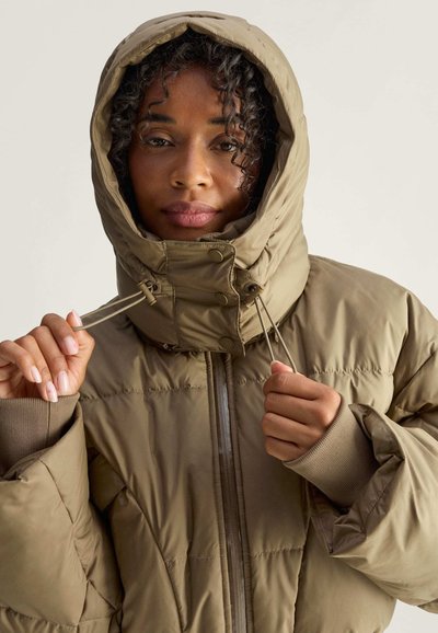 Olivgrüne Pufferjacke mit hohem Kragen und verstellbarem Kapuze. Sie hat einen Reißverschluss vorne, elastische Bündchen und eine gesteppten Textur.