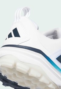 Λευκό αθλητικό παπούτσι με υφασμένο επάνω μέρος, μπλε και ναυτικό μπλε λεπτομέρειες, και εμφανές λάστιχο σόλας με εξογκώματα για πρόσφυση.