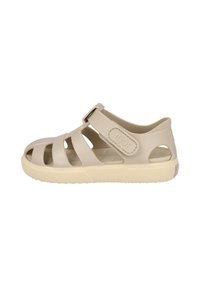 Sandalia beige con un diseño de tiras, fabricada en goma con una correa de velcro ajustable y suela texturizada para mayor agarre.