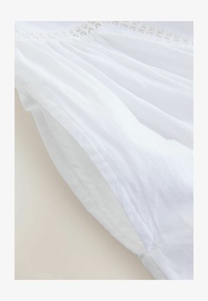 Material textil alb cu o dantelă texturată pe margine. Materialul pare ușor și ușor transparent, prezentând falduri moi și drapaje delicate.